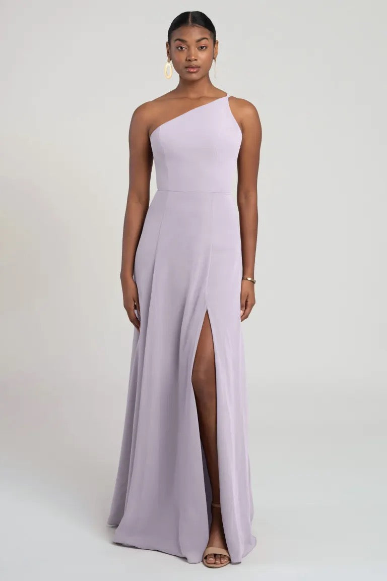 Woman in a sleek lavender chiffon one-shoulder gown with a side slit by Bergamot Bridal's Kora - Jenny Yoo Bridesmaid Dress.