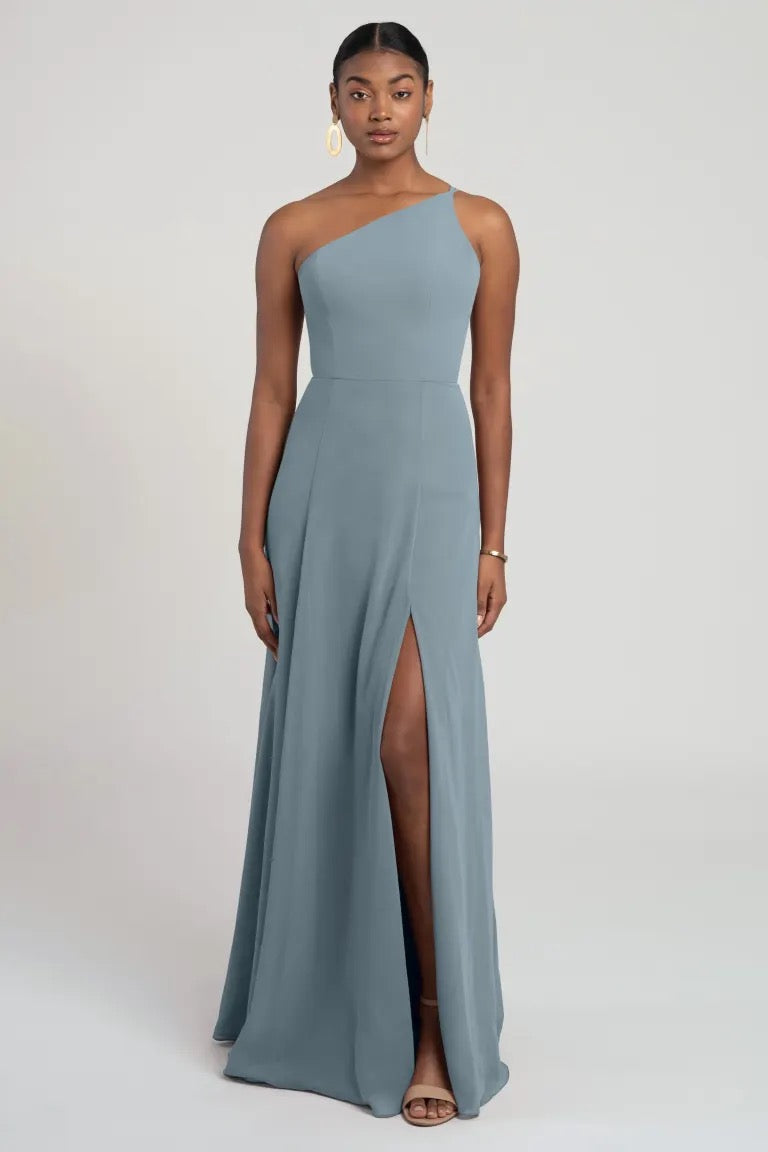 A woman wearing an elegant Kora - Jenny Yoo bridesmaid dress from Bergamot Bridal with a thigh-high slit, boasting a flattering fit and flare silhouette.