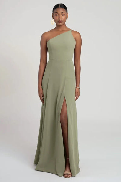 Woman in a flattering fit and flare, one-shoulder green Kora dress by Jenny Yoo Bridesmaid Dress with a side slit from Bergamot Bridal.