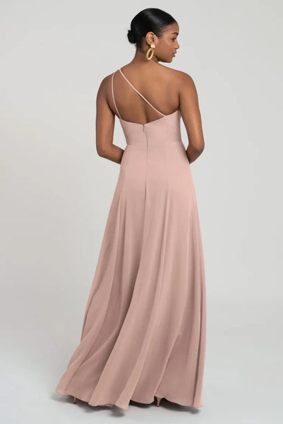 Woman from behind wearing an elegant one shoulder chiffon Kora - Jenny Yoo bridesmaid dress in pink with a flattering fit and flare silhouette from Bergamot Bridal.