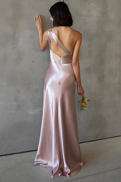 A woman in a Lena bridesmaid dress by Jenny Yoo, standing with her back to the camera and holding a bouquet of flowers.