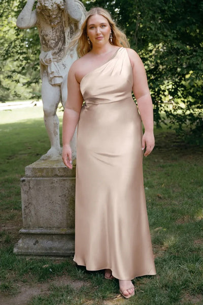 A woman in an elegant one-shoulder neckline Lena - Bridesmaid Dress by Jenny Yoo posing next to a statue in a park.