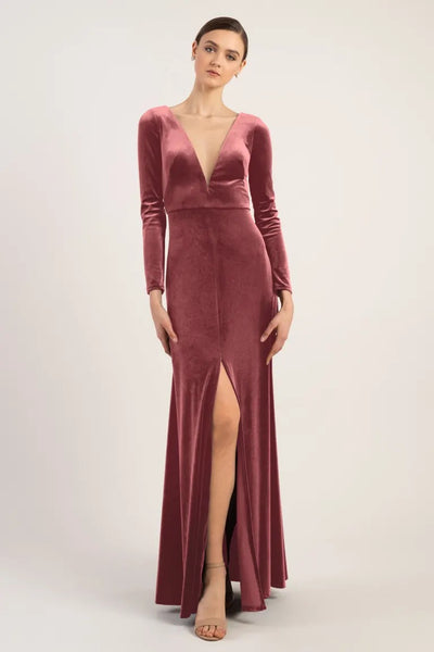 Model posing in a long-sleeved, deep v-neck Luxe Velvet Malia - Bridesmaid Dress by Jenny Yoo dress with a thigh-high slit from Bergamot Bridal.