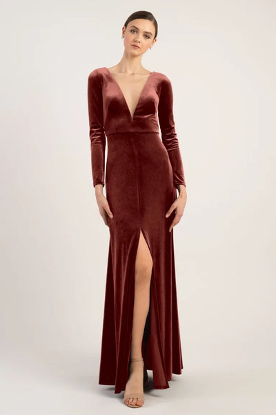 A woman in a Luxe Velvet, deep v-neck Malia - Bridesmaid Dress by Jenny Yoo with a thigh-high slit stands against a neutral background.