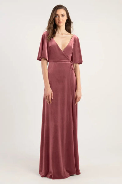 Woman posing in a long, Jenny Yoo Marin velvet bridesmaid dress with a deep V-neck and flutter sleeves from Bergamot Bridal.