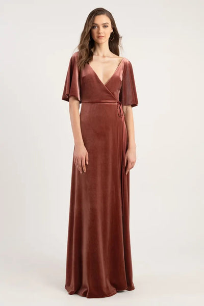 A woman modeling a full-length Jenny Yoo Marin velvet bridesmaid dress with flutter sleeves and a v-neckline from Bergamot Bridal.
