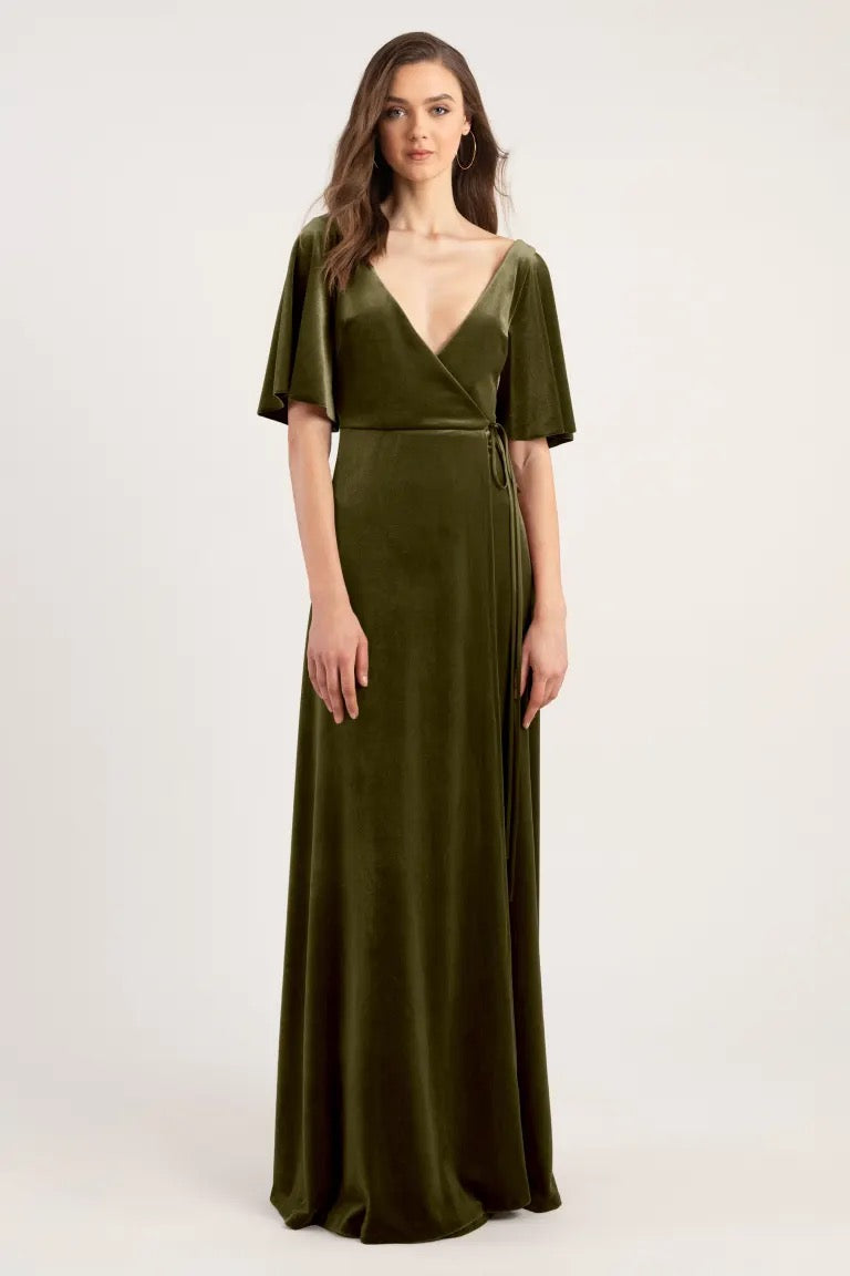 Woman posing in an elegant olive green Marin velvet evening dress with a deep V-neck and short sleeves by Jenny Yoo from Bergamot Bridal.