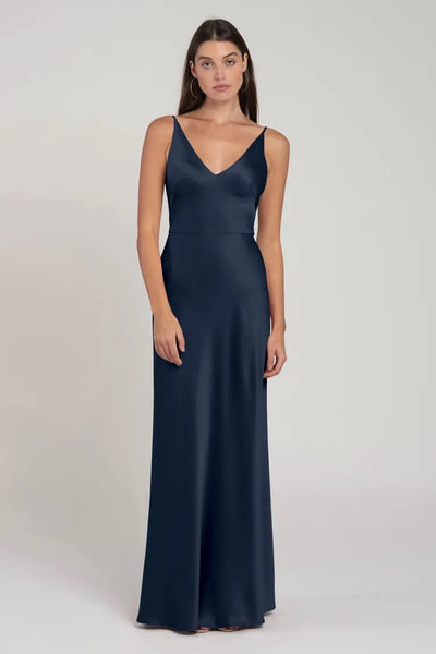 A woman wearing a navy blue satin bridesmaid dress with spaghetti straps and a flattering v-neckline, the Marla Bridesmaid Dress by Jenny Yoo from Bergamot Bridal.