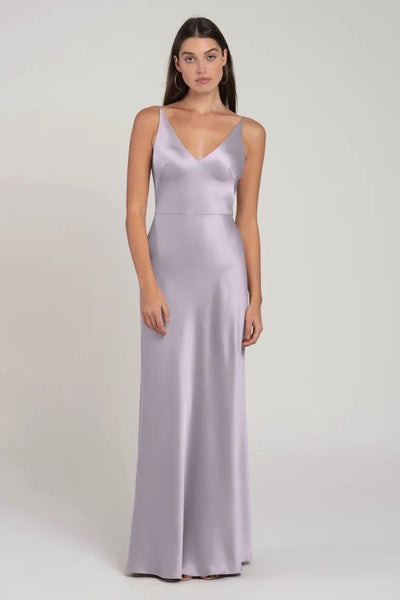 Woman posing in a long, light purple satin bridesmaid dress with spaghetti straps and a bias-cut skirt, the Marla - Bridesmaid Dress by Jenny Yoo from Bergamot Bridal.