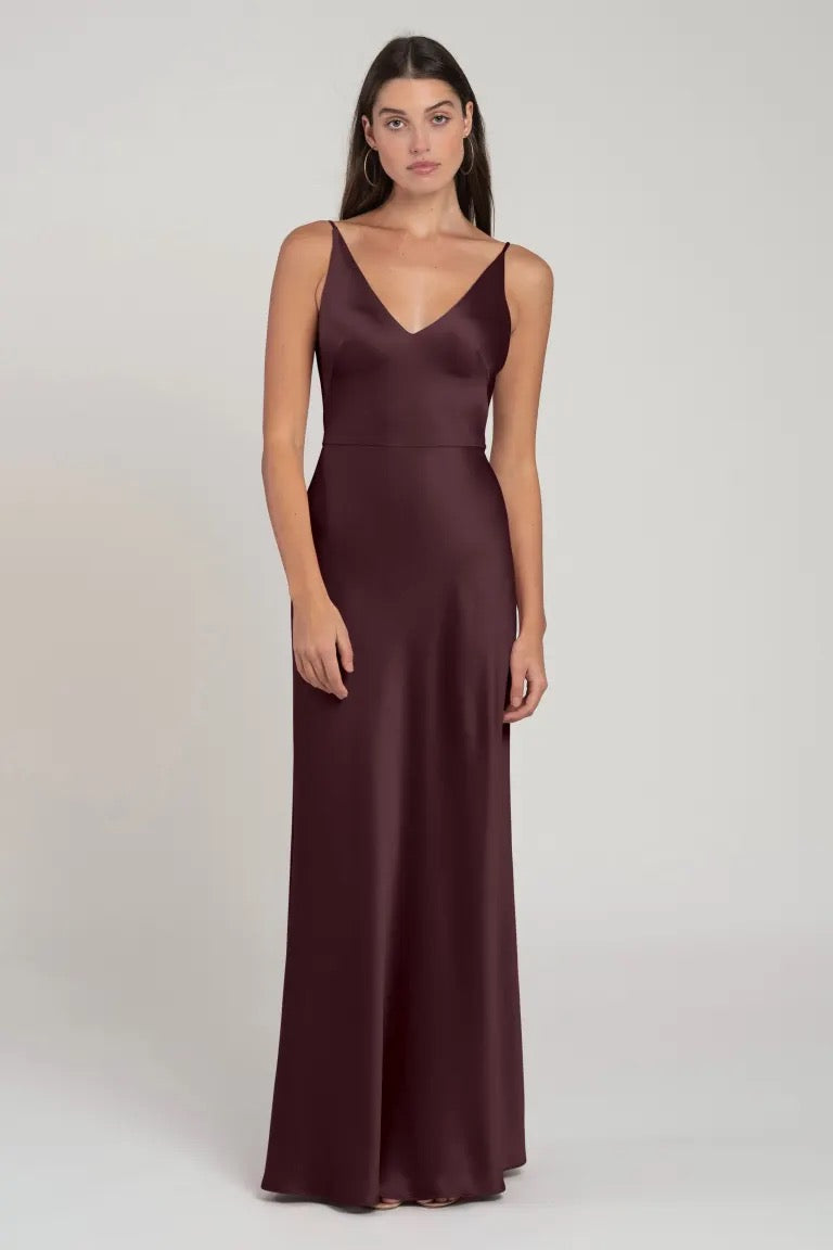 Woman posing in an elegant burgundy V-neck Marla bridesmaid dress by Jenny Yoo at Bergamot Bridal.