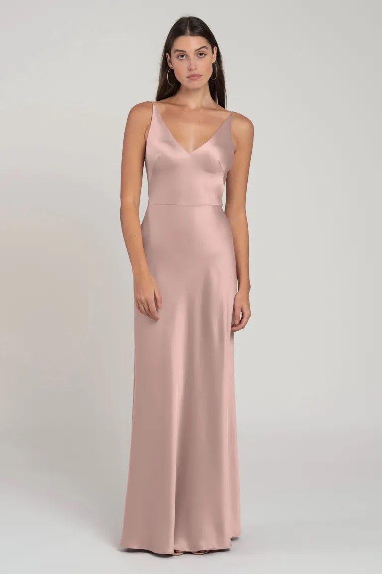 A woman models a sleek, bias-cut Marla bridesmaid dress by Jenny Yoo and blush pink slip dress with a v-neckline from Bergamot Bridal.