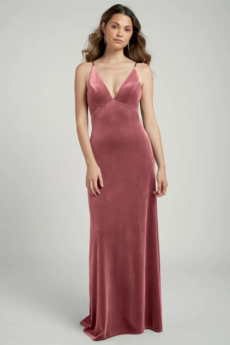 Woman posing in a long, pink Melanie velvet slip dress with a v-neckline - Woman posing in a long, pink "Bridesmaid Dress by Jenny Yoo" dress with a v-neckline.
