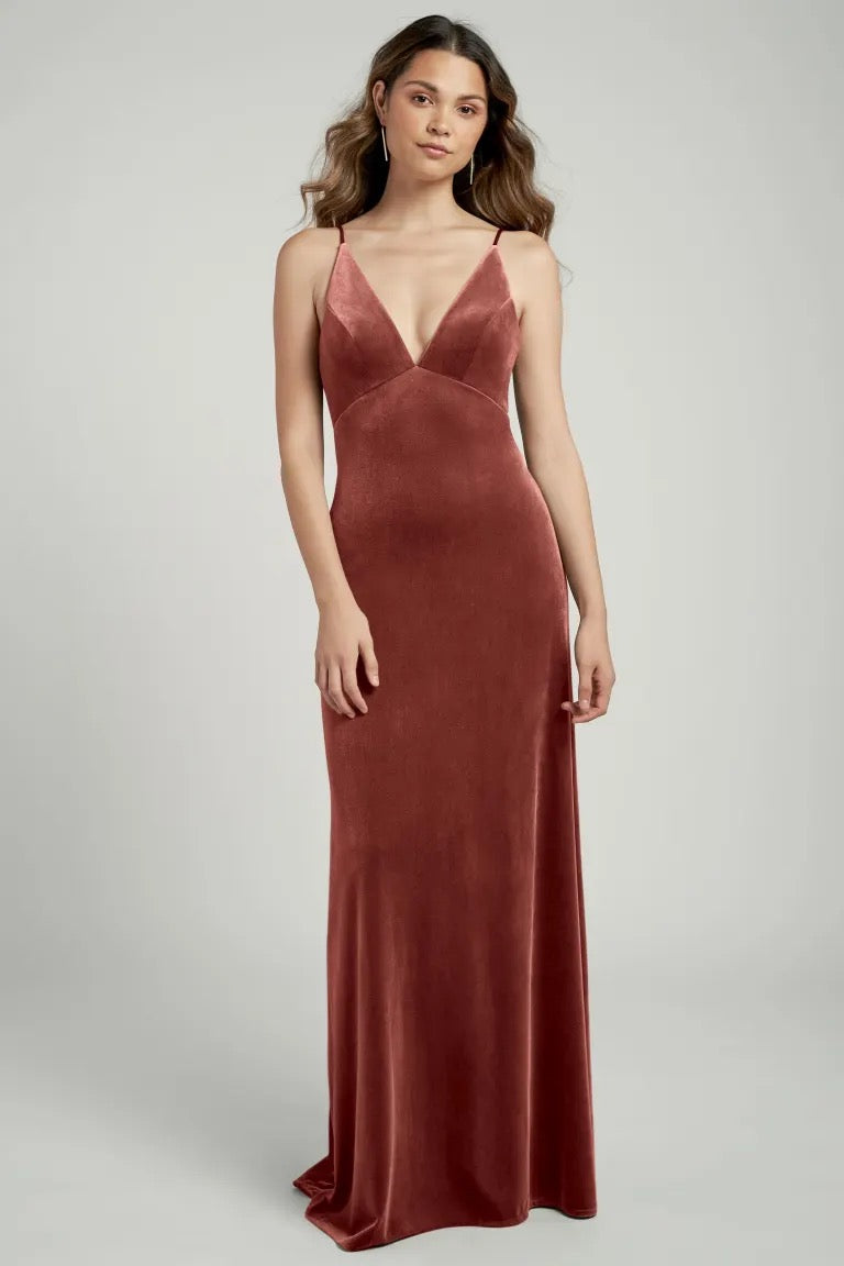 Woman in an elegant, rust-colored Melanie velvet evening gown with a bias cut skirt by Bergamot Bridal.