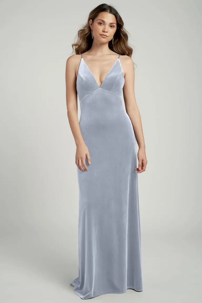 Woman in a long, slender, light blue velvet gown with a V-neckline by Bergamot Bridal featuring the Melanie Bridesmaid Dress by Jenny Yoo.