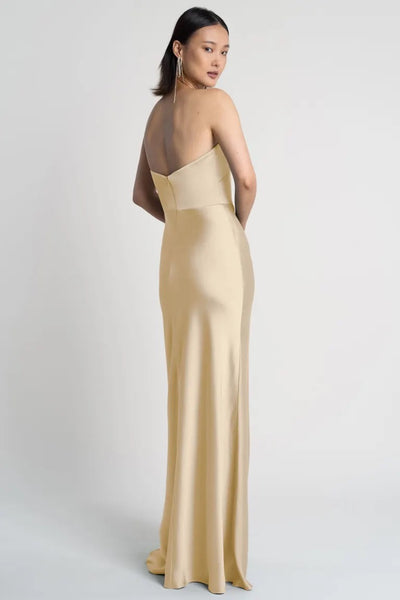 A woman posing in an elegant, strapless neckline cream evening gown, the Melody - Bridesmaid Dress by Jenny Yoo from Bergamot Bridal.