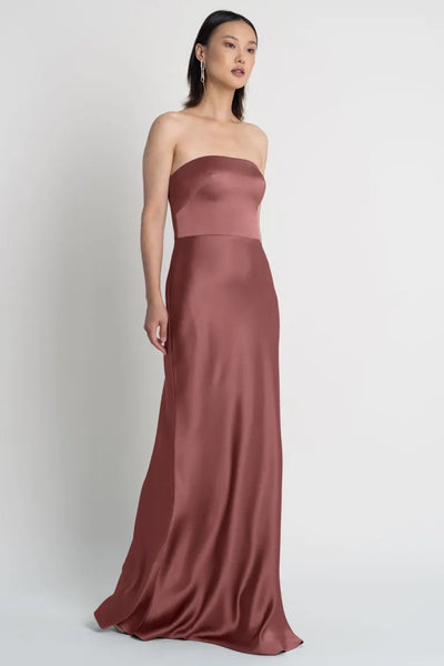 Woman wearing a strapless neckline Melody satin evening gown.
Product Name: Melody - Bridesmaid Dress by Jenny Yoo
Brand Name: Bergamot Bridal 
Revised Sentence: Woman wearing a strapless neckline Melody - Bridesmaid Dress by Jenny Yoo satin evening gown from Bergamot Bridal.