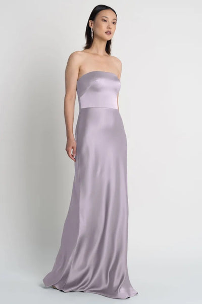 Woman posing in an elegant strapless Melody satin dress by Jenny Yoo with a bias-cut skirt from Bergamot Bridal.