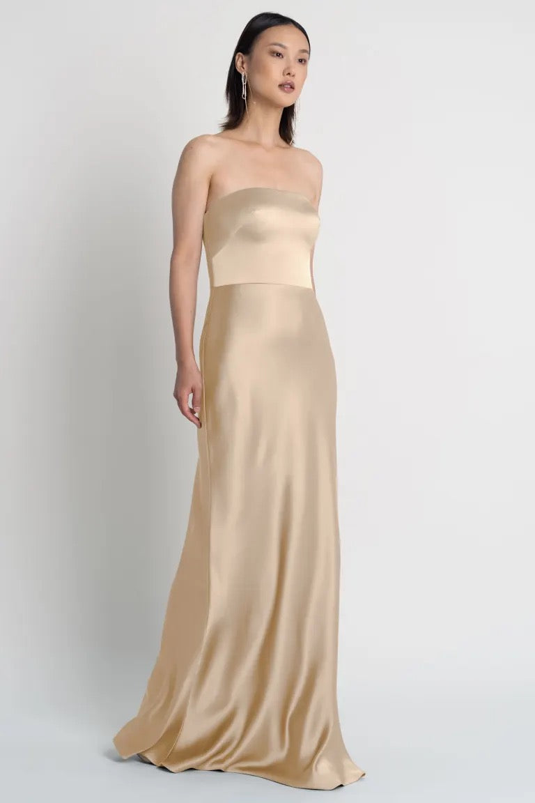 A woman models a Melody - Bridesmaid Dress by Jenny Yoo in beige satin from Bergamot Bridal.