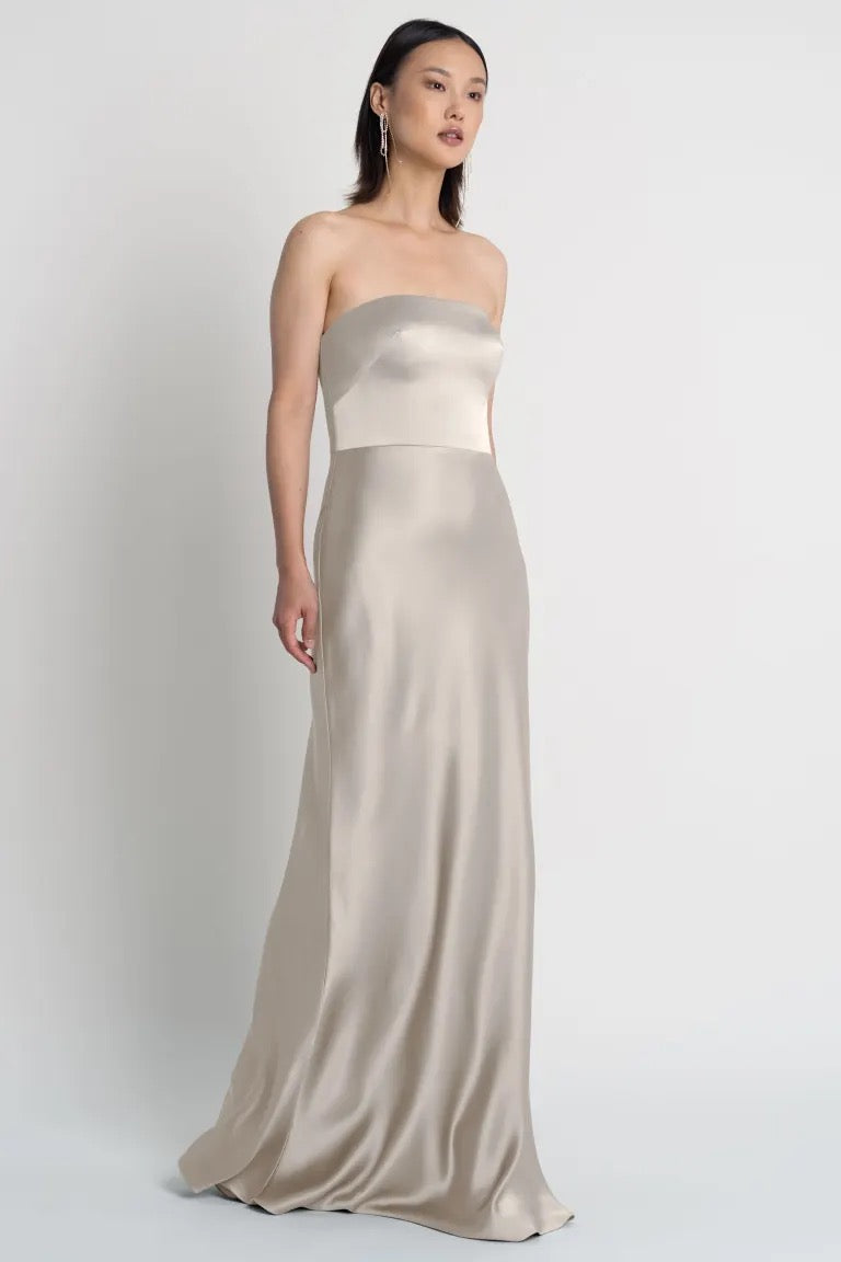 A woman models a strapless Melody bridesmaid dress by Jenny Yoo, featuring a bias-cut skirt, from Bergamot Bridal.