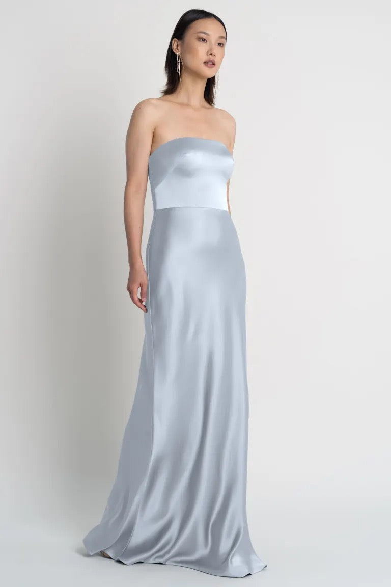 A woman wearing a strapless neckline Melody - Bridesmaid Dress by Jenny Yoo stands against a neutral background.