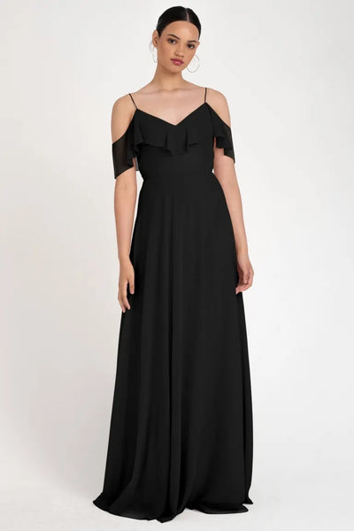 Woman wearing an elegant black off-the-shoulder Mila bridesmaid dress by Jenny Yoo with a flowing circle skirt, store sample size 22 from Bergamot Bridal.