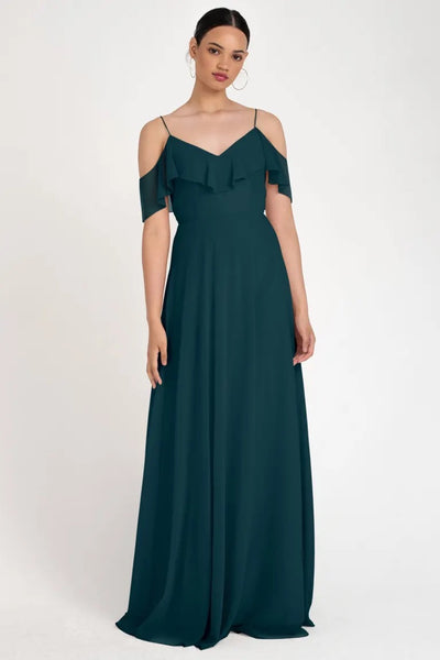 Woman in an elegant teal evening gown with an off-the-shoulder neckline and circle skirt silhouette, wearing the Mila bridesmaid dress by Jenny Yoo from Bergamot Bridal.