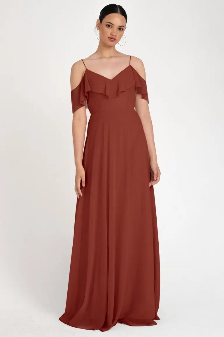 Woman in a long, russet off-the-shoulder gown with a circle skirt posing against a neutral background. 
Product: Mila - Bridesmaid Dress by Jenny Yoo
Brand: Bergamot Bridal