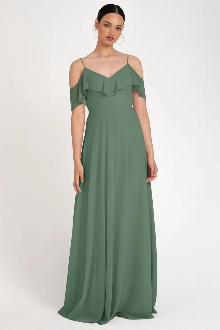 Woman in an elegant green off the shoulder neckline Mila bridesmaid dress by Jenny Yoo from Bergamot Bridal.