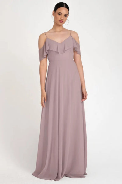 A woman wearing an elegant mauve Bergamot Bridal store sample size 22 off-the-shoulder maxi dress with ruffle detailing.