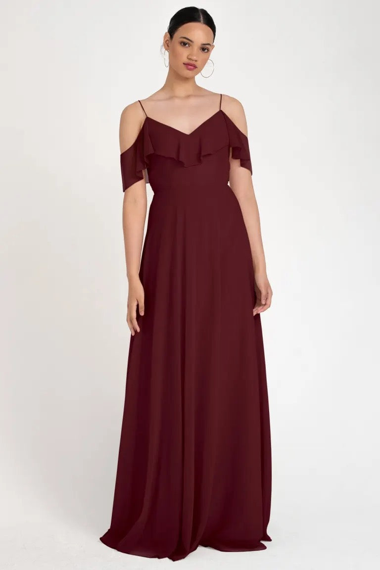 Woman modeling an elegant, burgundy off-the-shoulder Mila - Bridesmaid Dress by Jenny Yoo gown with a circle skirt from Bergamot Bridal.