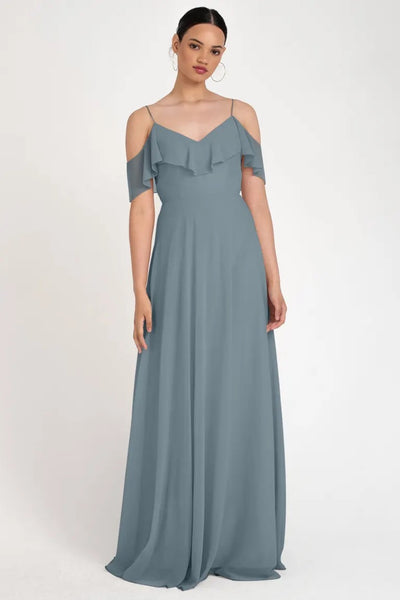 A woman modeling an elegant gray evening gown with an off-the-shoulder neckline, the Mila - Bridesmaid Dress by Jenny Yoo from Bergamot Bridal.