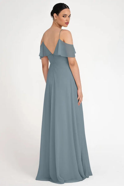 Woman in an elegant grey off-the-shoulder gown with a circle skirt, looking over her shoulder, wearing the Mila - Bridesmaid Dress by Jenny Yoo from Bergamot Bridal.