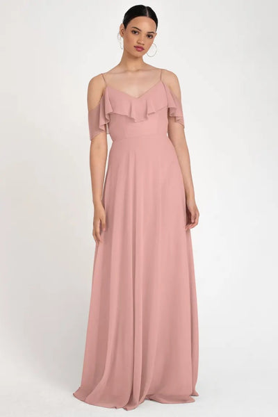 Woman in a Mila - Bridesmaid Dress by Jenny Yoo in pastel pink with an off-the-shoulder circle skirt and ruffle detail from Bergamot Bridal.