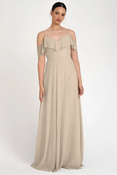 Woman in an elegant beige Mila bridesmaid dress by Jenny Yoo with off-the-shoulder ruffle detailing and a circle skirt from Bergamot Bridal.