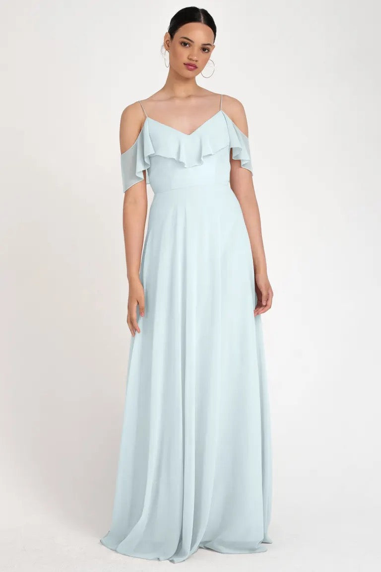 Woman posing in a store sample Mila - Bridesmaid Dress by Jenny Yoo size 22 light blue off-the-shoulder gown with a circle skirt silhouette at Bergamot Bridal.