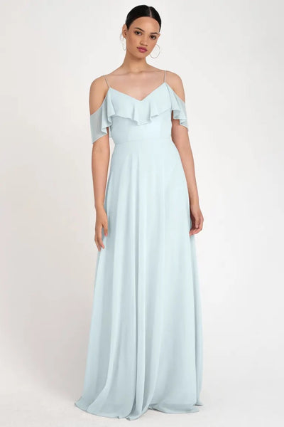 Woman posing in a store sample Mila - Bridesmaid Dress by Jenny Yoo size 22 light blue off-the-shoulder gown with a circle skirt silhouette at Bergamot Bridal.