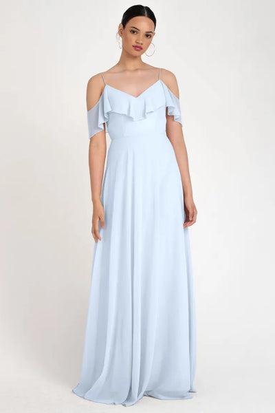 A woman in a light blue, store sample size 22, off-the-shoulder Mila bridesmaid dress by Jenny Yoo with ruffle detailing from Bergamot Bridal.