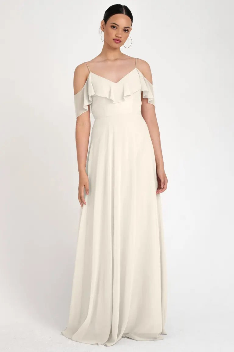 Woman in an elegant off-the-shoulder neckline cream Mila - Bridesmaid Dress by Jenny Yoo, store sample size 22 from Bergamot Bridal.