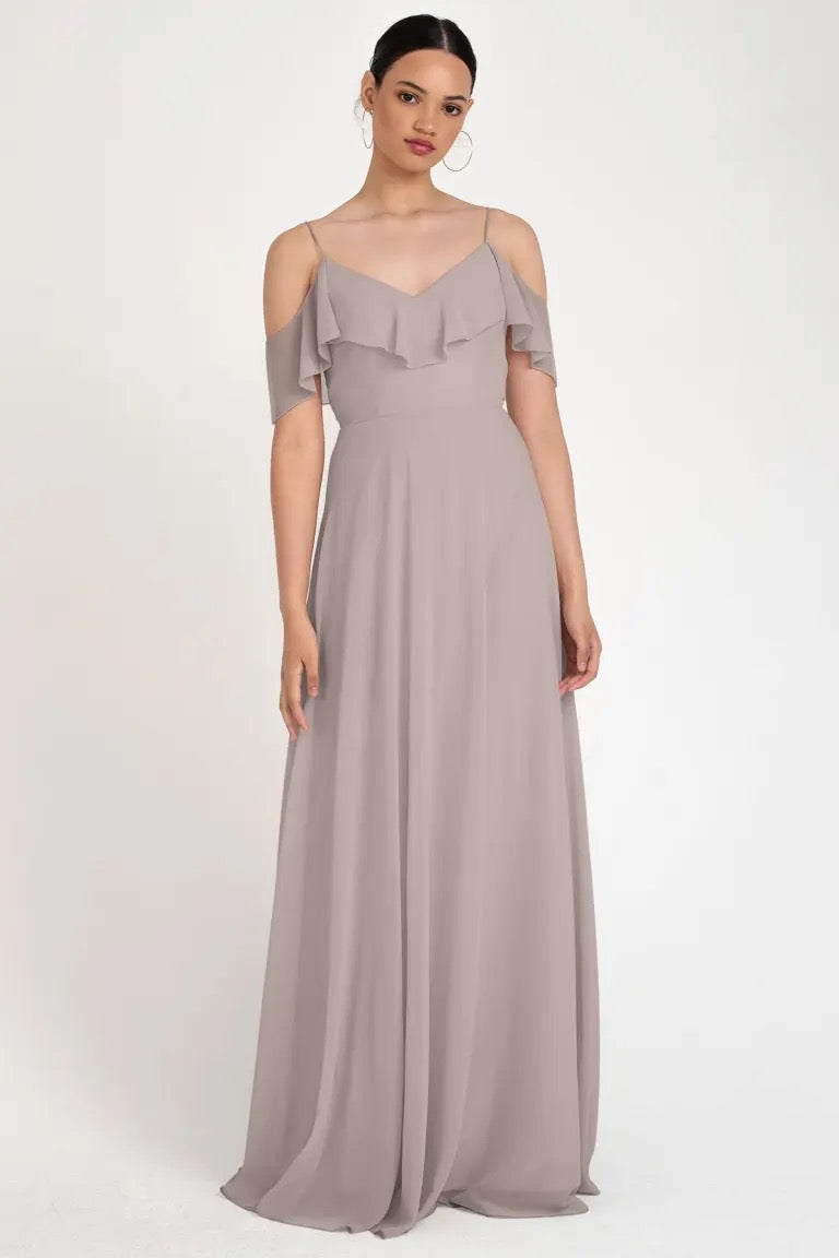 Woman in a gray evening gown with off-the-shoulder sleeves, the Mila Bridesmaid Dress by Jenny Yoo at Bergamot Bridal.