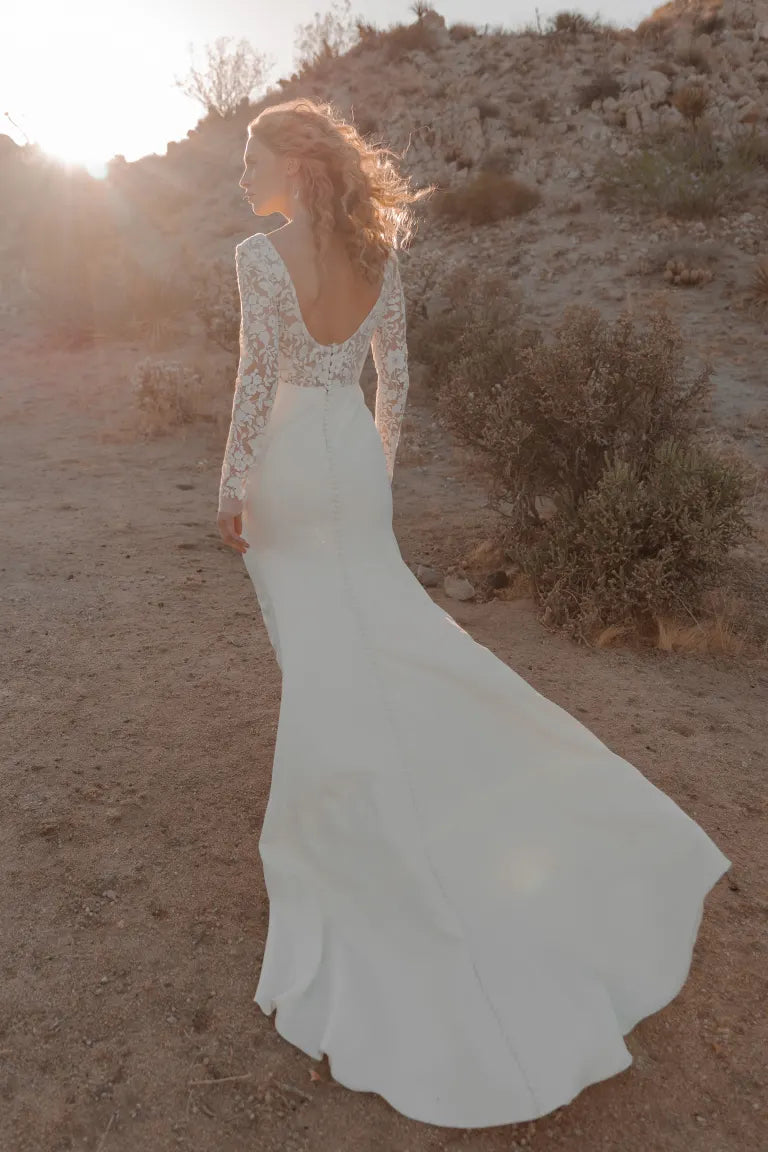 Woman in a Julian - Jenny Yoo wedding dress from Bergamot Bridal, embroidered with florals, looking away in a desert at sunset.