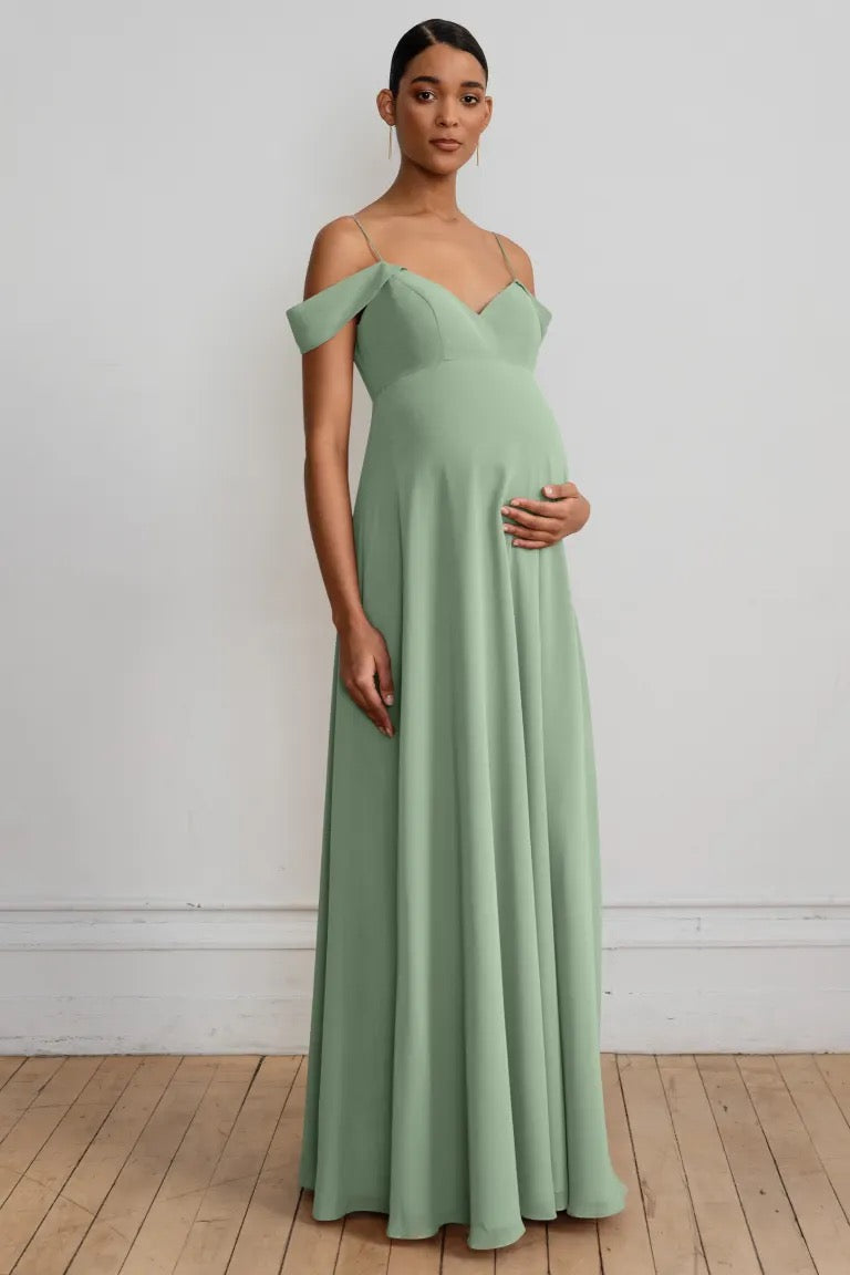A pregnant woman wearing an off-the-shoulder Jenny Yoo Priya V-neck chiffon bridesmaid dress, standing against a neutral background from Bergamot Bridal.