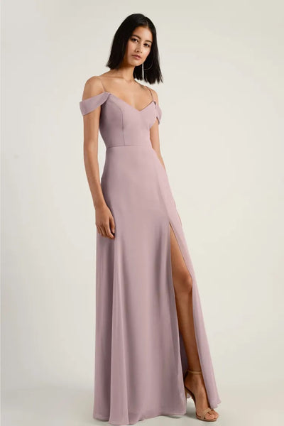 Woman in an elegant off-the-shoulder mauve chiffon Priya bridesmaid dress by Jenny Yoo with a high side slit from Bergamot Bridal.
