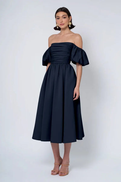 Woman in an off-the-shoulder navy Jenny Yoo Bridesmaid Dress with heeled sandals from Bergamot Bridal.