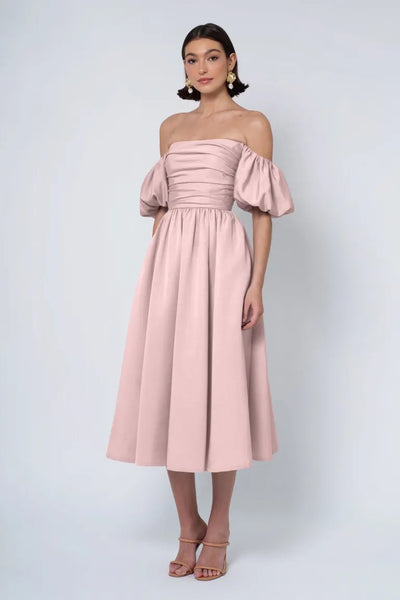 Woman posing in a pink Jenny Yoo Bridesmaid Dress with a strapless neckline, puff sleeves, and heels from Bergamot Bridal.