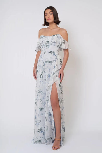 A woman posing in a Salma Print - Jenny Yoo Bridesmaid Dress chiffon off-the-shoulder gown with a side slit from Bergamot Bridal.