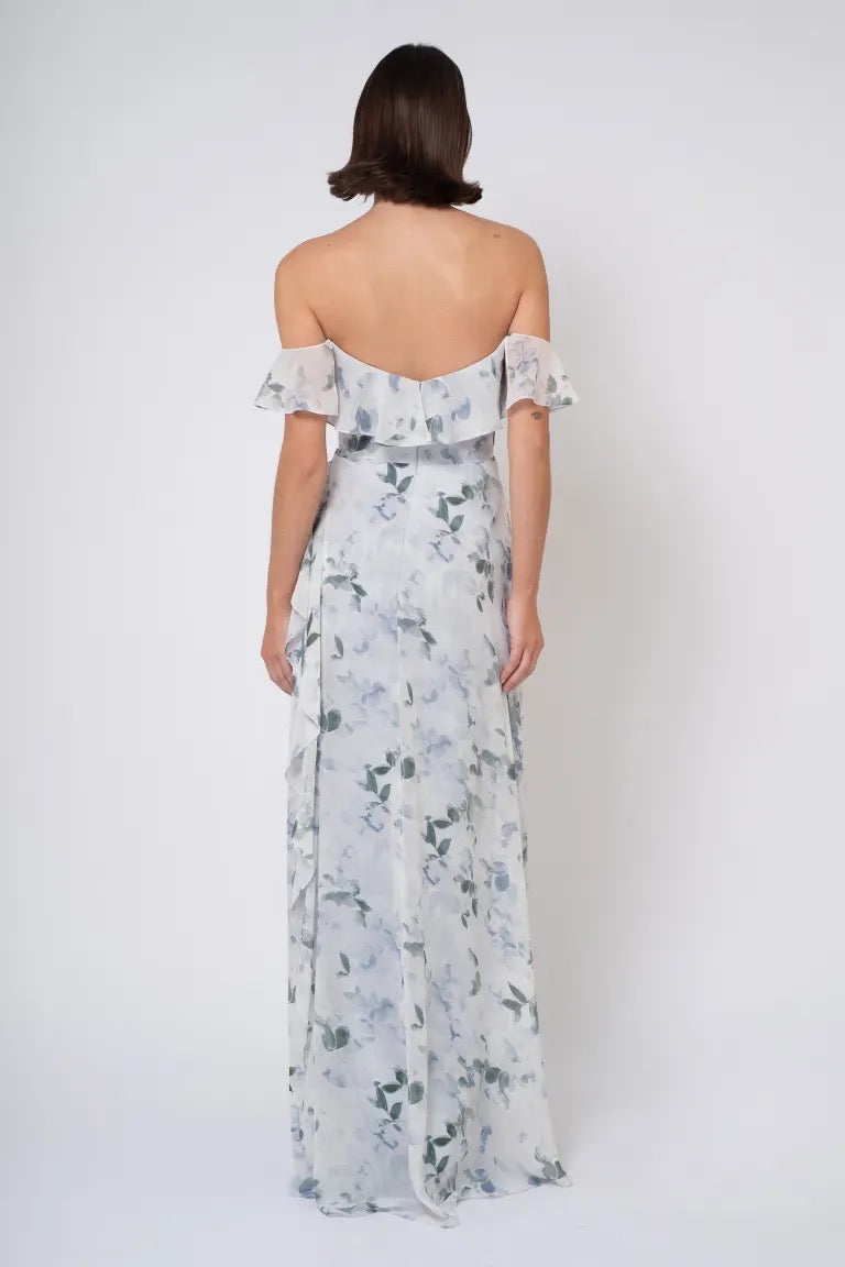 Woman wearing an off-the-shoulder Salma Print - Jenny Yoo Bridesmaid Dress with a side slit, viewed from the back by Bergamot Bridal.