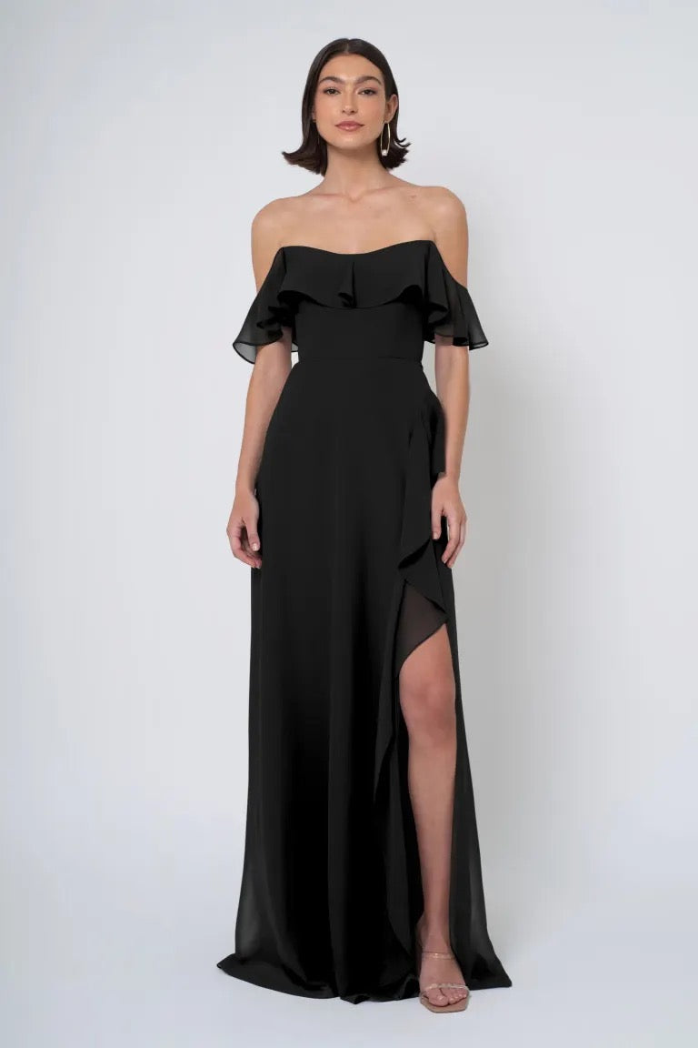 Woman posing in a Jenny Yoo Bridesmaid Dress chiffon off-the-shoulder evening gown with a side slit from Bergamot Bridal.