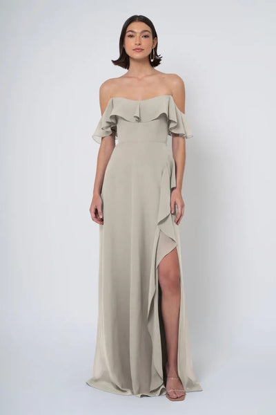 Woman in an elegant, off the shoulder neckline, beige Jenny Yoo Bridesmaid Dress with a side slit from Bergamot Bridal.