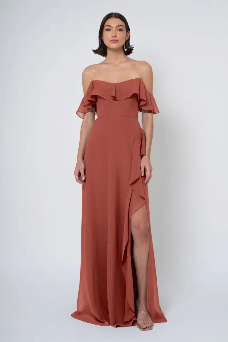 Woman in an elegant Salma - Jenny Yoo Bridesmaid Dress with an off-the-shoulder neckline and a side slit from Bergamot Bridal.