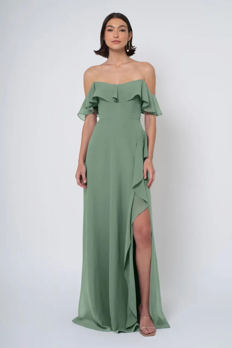 A woman in an elegant Salma - Jenny Yoo bridesmaid dress, off the shoulder with a side slit from Bergamot Bridal.